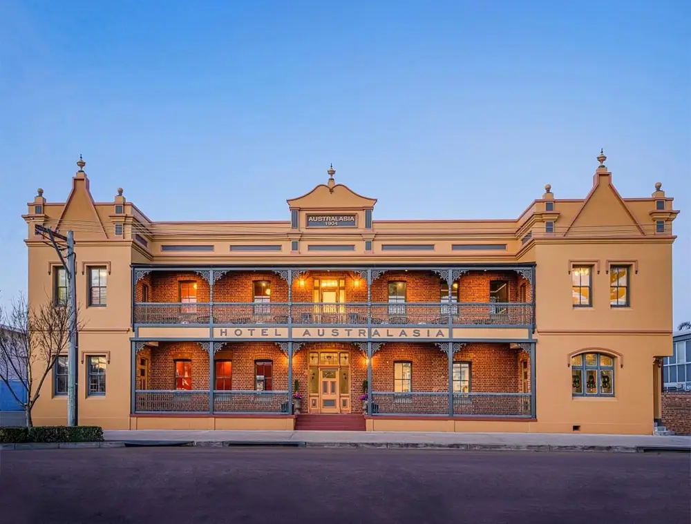 Exterior view of Hotel Australasia at twilight showcasing vintage architecture and electric lighting | Eastman Electrical